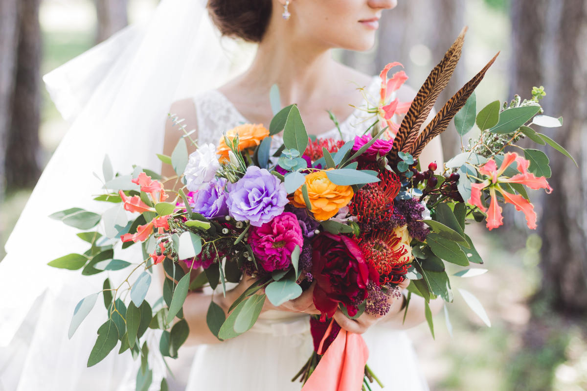 Ein großer Blumenstrauß im Boho Stil wird von einer Braut gehalten.
